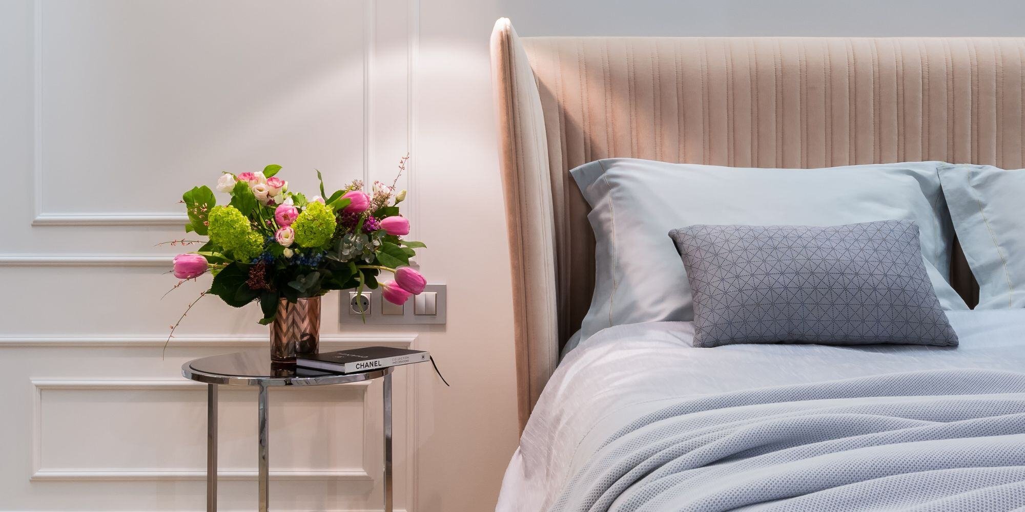 bedroom with white box trimmed walls and lighting over the bed