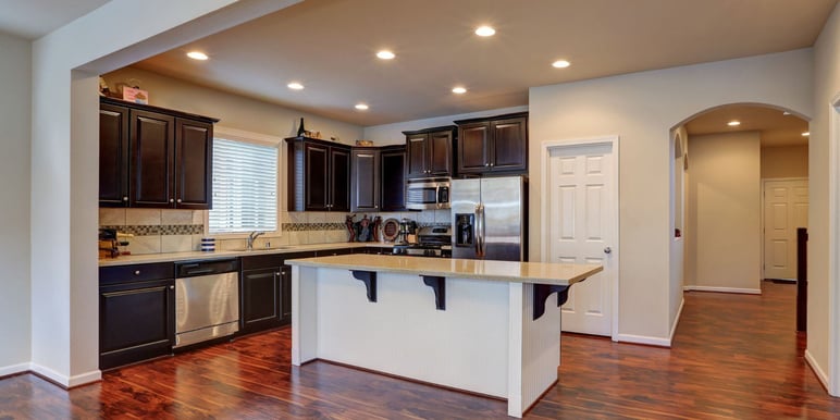 finished basement remodel with black cabinets, dark wood floors, and a kitchen island