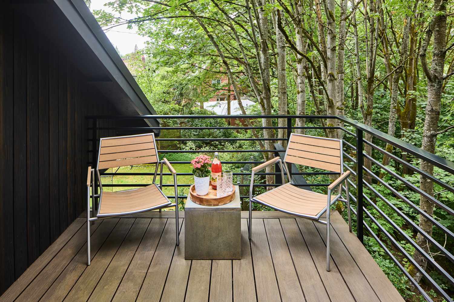 Elevated wood balcony with modern chairs and forest views at Pathway Design & Construction’s Treetop Retreat in Seattle, WA.-optimized