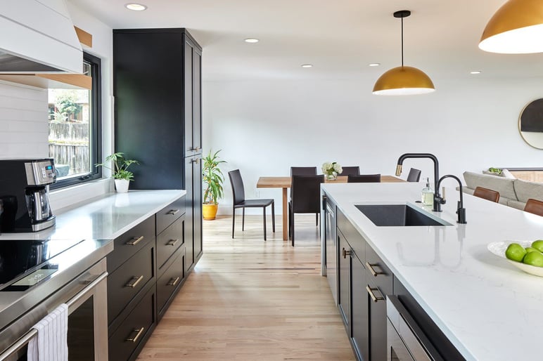sleek modern kitchen addition with black cabinets, white countertop, and hardwood floors in seattle