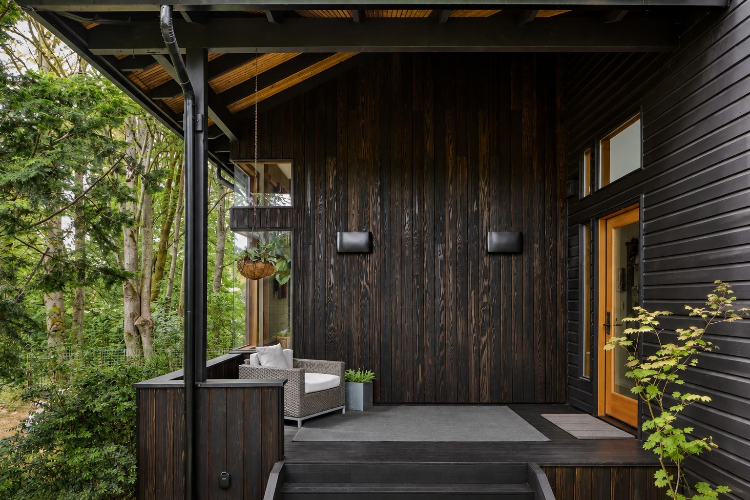 Modern covered porch with charred wood siding, exposed timber beams, and forest views on a custom home remodel in Renton, WA Modern covered porch with charred wood siding, exposed timber beams, and forest views on a custom home remodel in Renton, WA