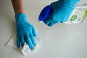 gloved hands holding a cleaning solution spray bottle