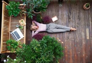 woman laying on a deck outside with plants