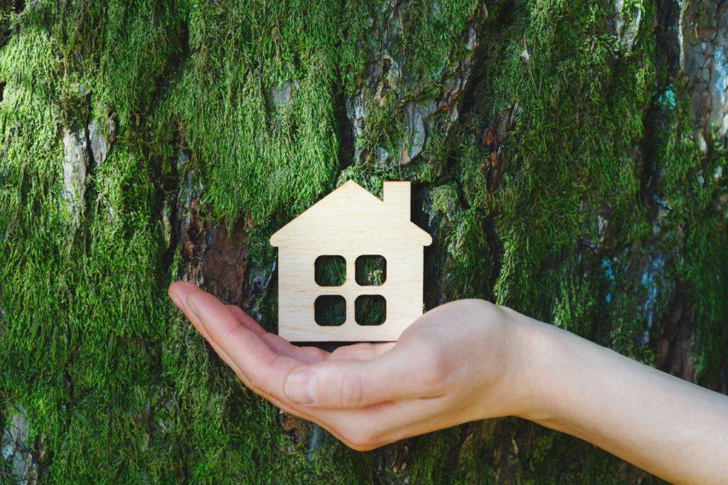 hand holding a small wooden cutout of a house